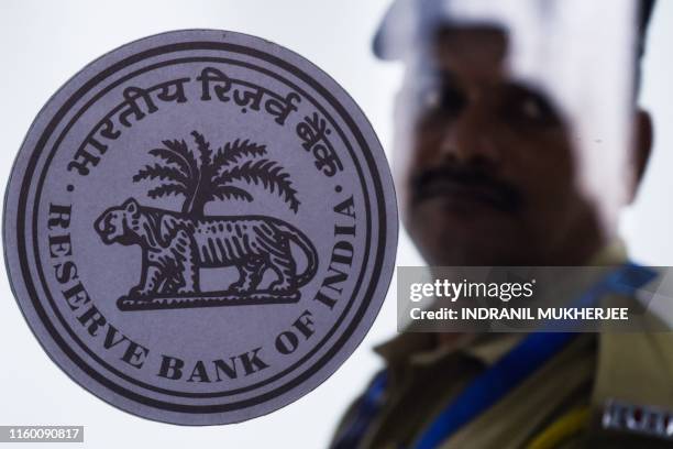 Security guard stands behind a logo of India's central bank, Reserve Bank of India , at RBI headquarters in Mumbai on August 7, 2019. - India's...