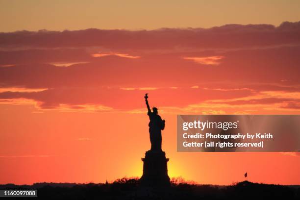 brooklyn nyc road trip: sunsetting behind the statue of liberty - the sun sets behind the statue of liberty stock pictures, royalty-free photos & images