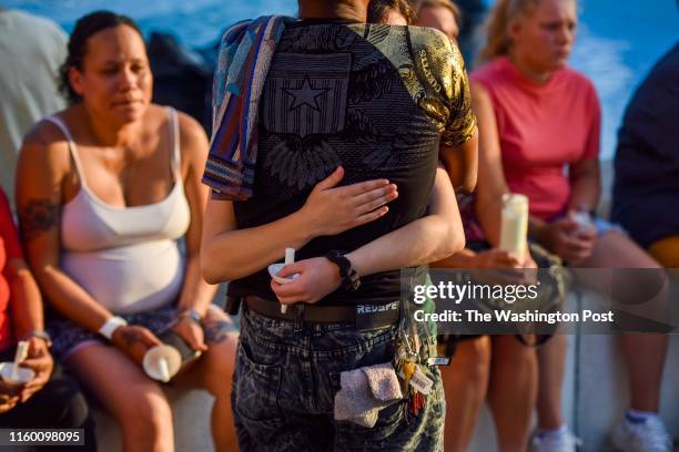 Roderick Fudge, brother of Derrick Fudge, is hugged by his unnamed granddaughter as mourners gather for a vigil on Monday, August 5 in Springfield,...