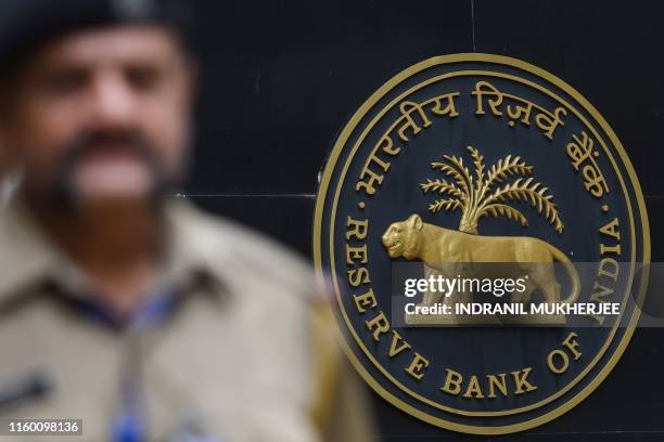 Security staff walks past the logo of Reserve Bank of India at the RBI headquarters in Mumbai on August 7, 2019. - India's central bank on August 7...