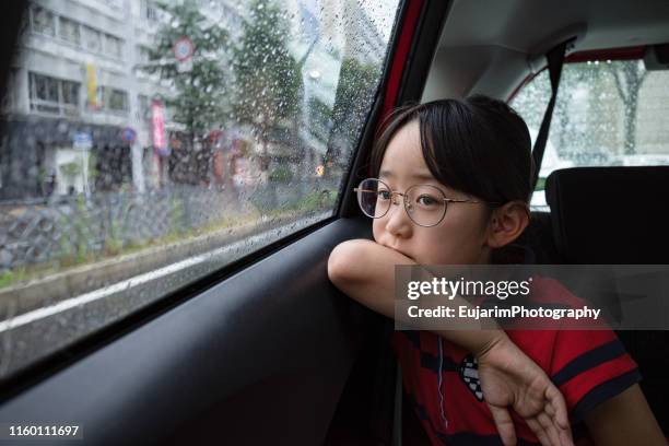 cute japanese girl looking out of the car window on a rainy day - rainy season stock-fotos und bilder