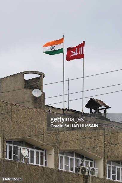 In this picture taken on August 6, 2019 an Indian national flag flies next to a Jammu and Kashmiri flag ontop of a building during a curfew in...