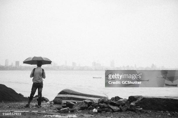 homme admirant l'horizon lointain de mumbai près de marine drive, mumbai - enjoy monsoon photos et images de collection