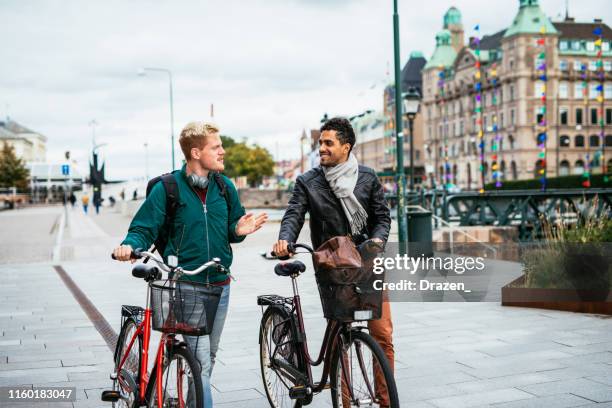 gay couple riding bicycles - malmö stock pictures, royalty-free photos & images