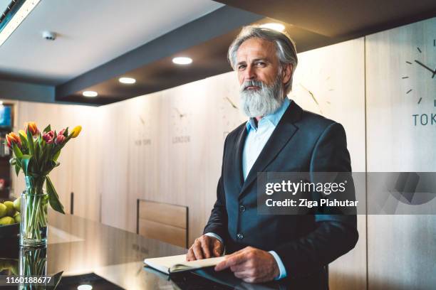 una recepcionista masculina con canas y barba con traje - recepcionista hotel fotografías e imágenes de stock