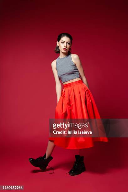 skinny young woman in red skirt posing in studio - skirt stock-fotos und bilder