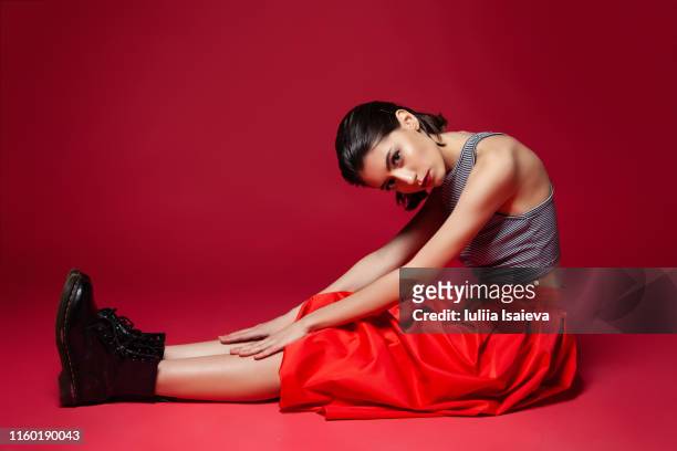 slender stylish female sitting on red background - art modeling studio stock pictures, royalty-free photos & images