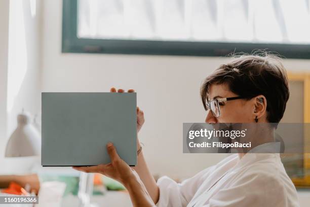 jeune femme adulte regardant la liaison d'un cahier - reliure de livre photos et images de collection