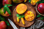 Tropical Fruits: Sliced mangos in a wooden plate on a table in rustic kitchen