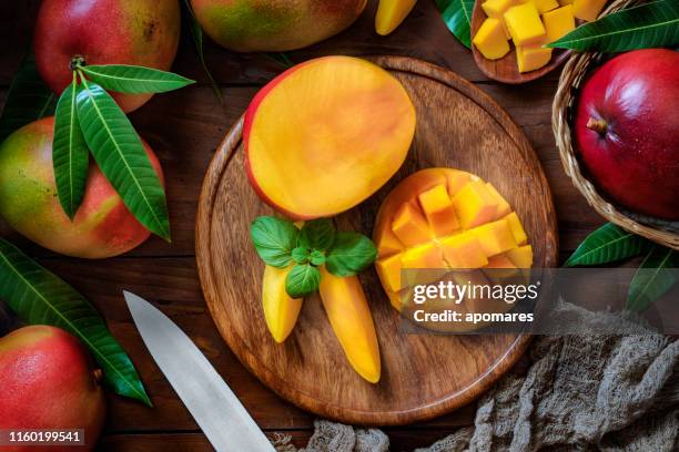 tropical fruits: sliced mangos in a wooden plate on a table in rustic kitchen - mango fruit stock pictures, royalty-free photos & images