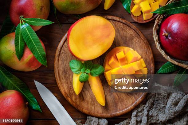 tropical fruits: sliced mangos in a wooden plate on a table in rustic kitchen - loiça imagens e fotografias de stock
