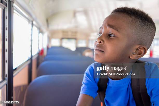 il giovane ragazzo guarda preoccupato fuori dal finestrino dell'autobus - scared boy foto e immagini stock