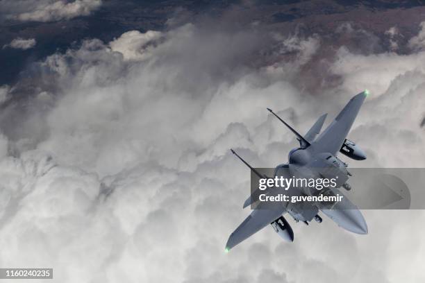 f-15 straaljager vliegen over wolken - militair vliegtuig stockfoto's en -beelden