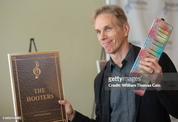 Rob Hyman of The Hooters holds a Hohner melodica as he speaks with the media after his band was nominated for induction during the announcement of...