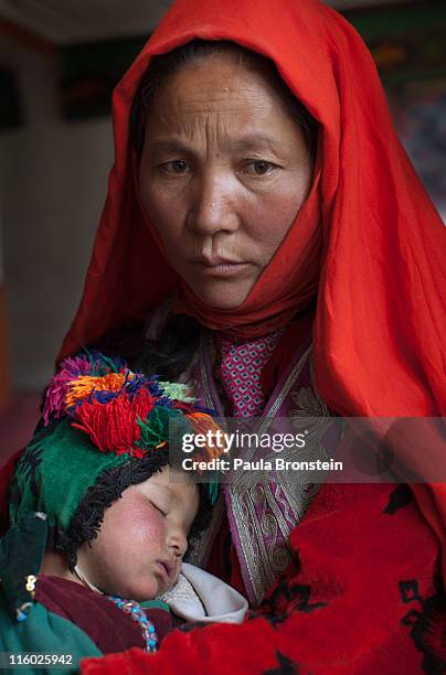 Hazara woman holds her baby while waiting to see the doctor at a mosque, makeshift mobile health clinic June 12 in the village of Gharmboloq, in...