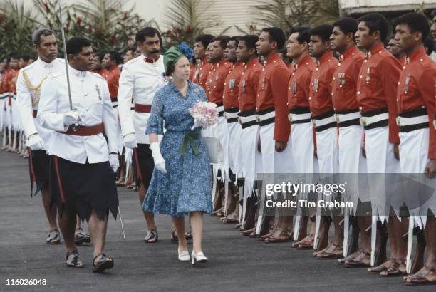 Queen Elizabeth II, carrying a small bouquet of flowers, inspecting a guard of honour at Nadi airport in Nadi, Fiji, 30 October 1982. The Queen was...