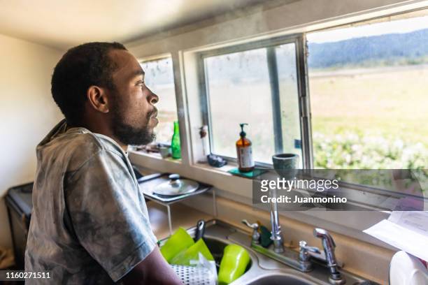 serious black mid adult man looking through a window - mid adult men stock pictures, royalty-free photos & images