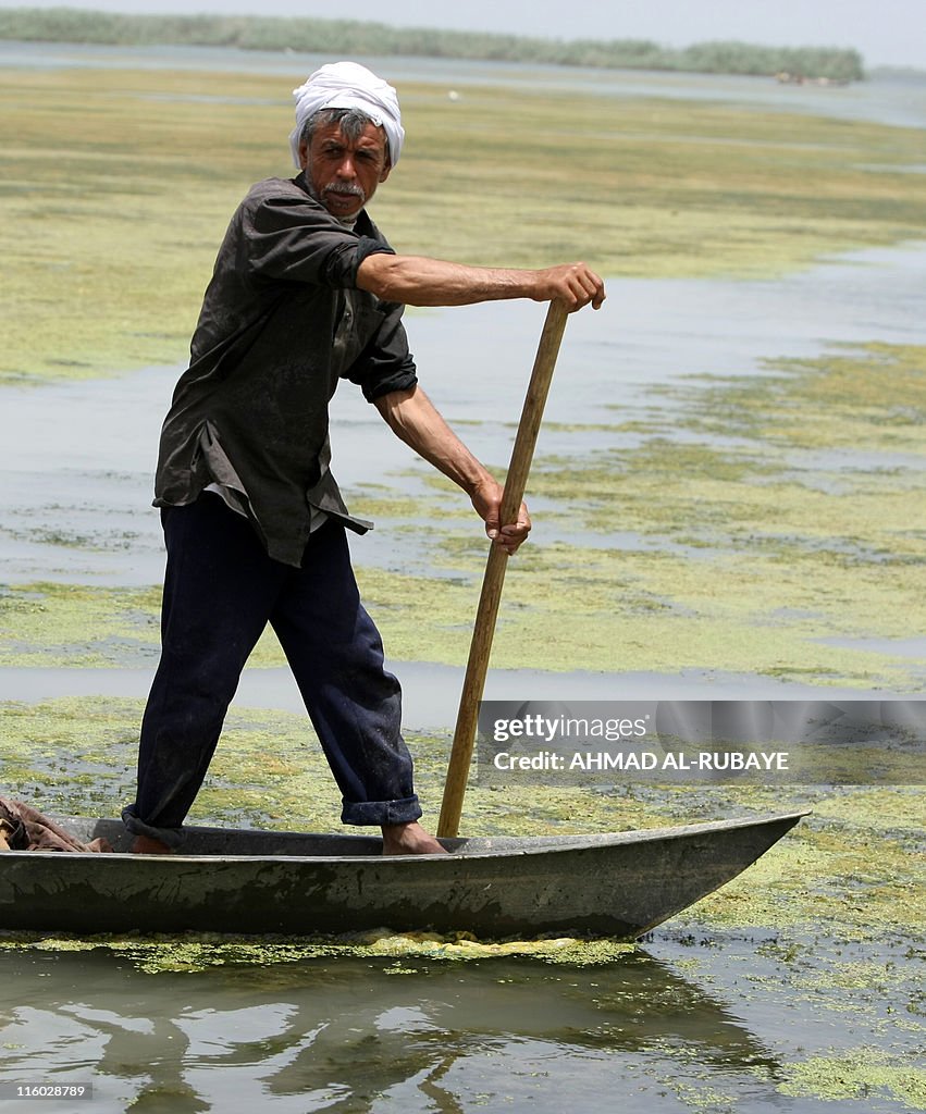 An Iraqi fisherman pushes his dug-out on