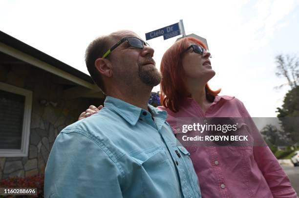 Tourists Glenn Martin and Peggy Miles survey the area on Cielo Drive during a Dearly Departed Tour related to the Manson Family murders in Beverly...