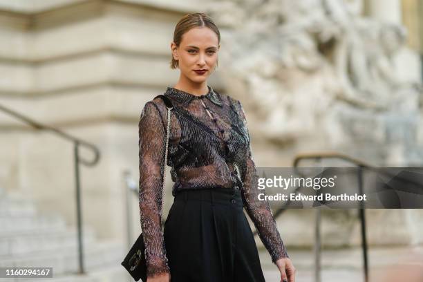 Nora Arnezeder wears a glittery bead embroidered black transparent shirt, a black bag, black wide-legs pants, outside Armani, during Paris Fashion...