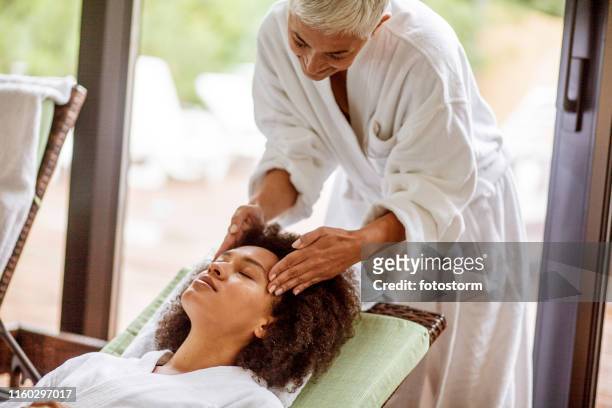 mujer joven recibiendo un masaje de cabeza - head massage fotografías e imágenes de stock