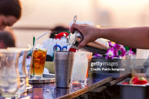 bartender pouring cocktail in a bar on rooftop - bar front stock-fotos und bilder