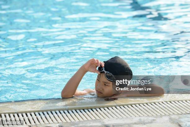 boy resting beside the pool - boy swimming pool goggle and cap stock pictures, royalty-free photos & images