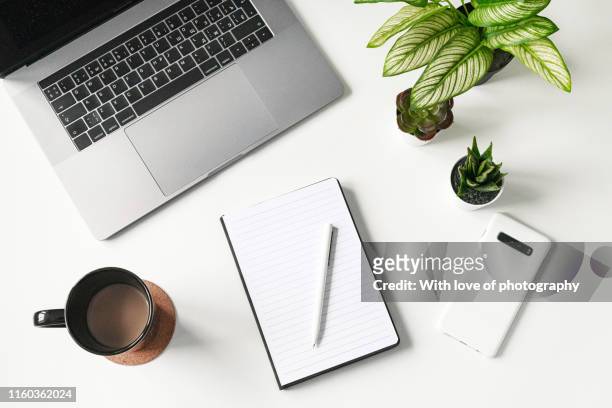 modern white office desk table with laptop, smartphone and blank notebook and cup of coffee, flatlay, top view workspace, business - office desk top view fotografías e imágenes de stock