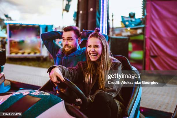 scared boyfriend letting girlfriend drive bumper car - roller coaster people stock pictures, royalty-free photos & images