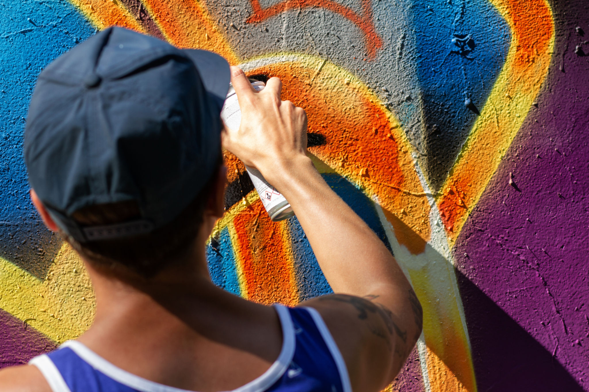 Workshopteilnehmer sprüht mit Cap und Dose ein buntes Graffiti auf eine Wand. Workshopteilnehmer sprüht mit Cap und Dose ein buntes Graffiti auf eine Wand.