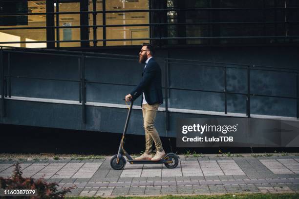 hipster auf einem roller in der stadt - tretroller stock-fotos und bilder