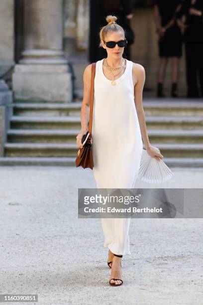 Lena Perminova wears a white dress, a brown Valentino leather bag, golden necklace, sandals outside Valentino, during Paris Fashion Week -Haute...