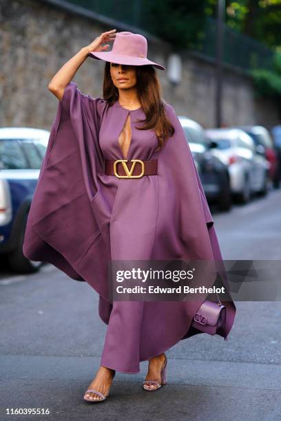 Janet Mock wears a purple hat, a purple dress, a brown large Valentino leather belt, outside Valentino, during Paris Fashion Week -Haute Couture...