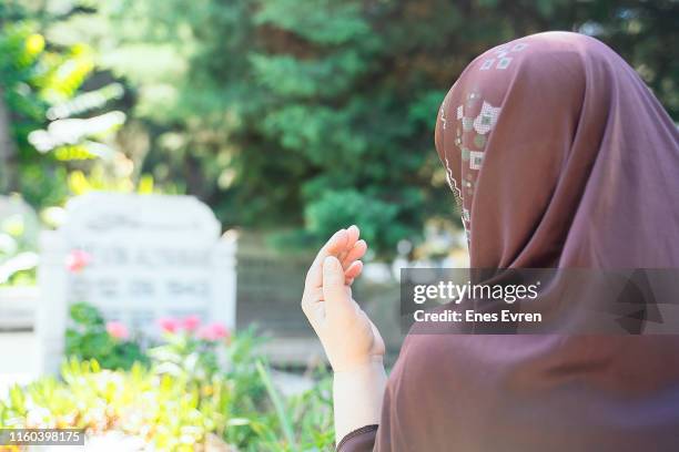 muslim woman praying in cemetery - rear view - churchyards stock pictures, royalty-free photos & images