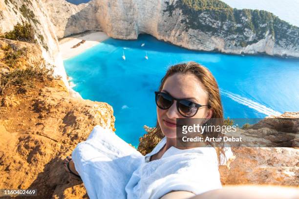 woman taking a selfie from viewpoint of the famous shipwreck beach in greece. - greek woman stock-fotos und bilder