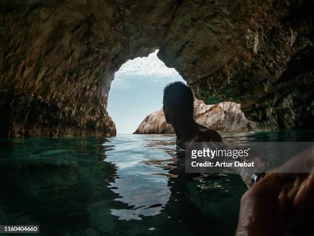 guy exploring the caves in the greece coastline with action camera. - extreme angle stock pictures, royalty-free photos & images