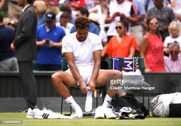 Jo-Wilfred Tsonga of France changes his socks between change of serve in his Men's Singles third round match against Rafael Nadal of Spain during Day...