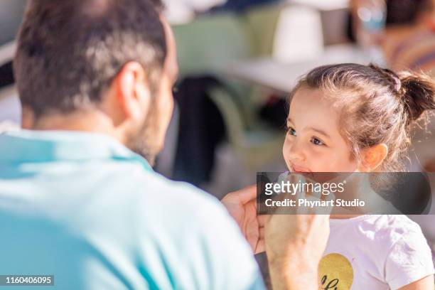 padre limpia la boca de su hija con un papel tisú - paper napkin fotografías e imágenes de stock