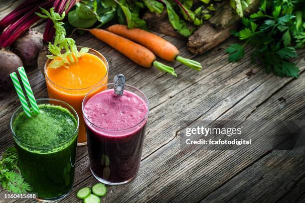 gemüsegetränke: rüben-, karotten- und grüne gemüsesäfte auf rustikalem holztisch. kopierspeicherplatz verfügbar - avocado smoothie stock-fotos und bilder