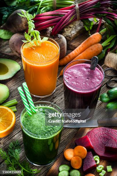 vegetable drinks: beet, carrot and green vegetables juices on rustic wooden table - avocado smoothie stock pictures, royalty-free photos & images