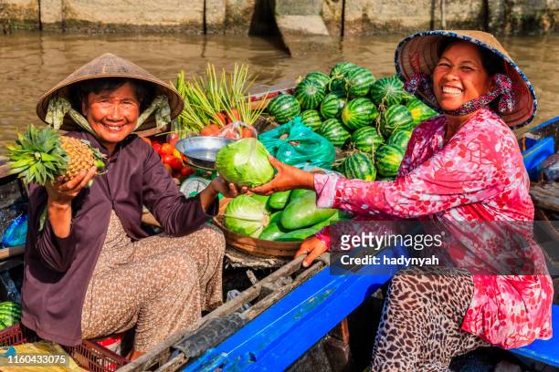 femme vietnamienne vendant des fruits sur le marché flottant, delta du fleuve de mékong, vietnam - marché flottant photos et images de collection