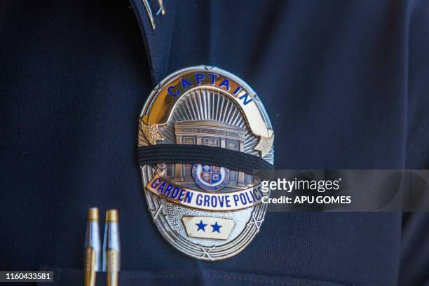 Police officer wears a badge with a mourning band during a press conference on August 8, 2019 in front of the Garden Grove Police Department after a...