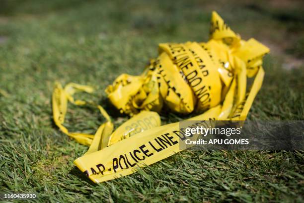 Bundle of police crime scene tape is left on front of the 7-eleven shop in Santa Ana, California on August 08, 2019 where a security guard was...