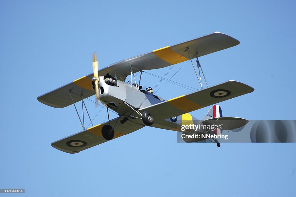 Biplane R80 Tiger Moth flying in clear blue sky