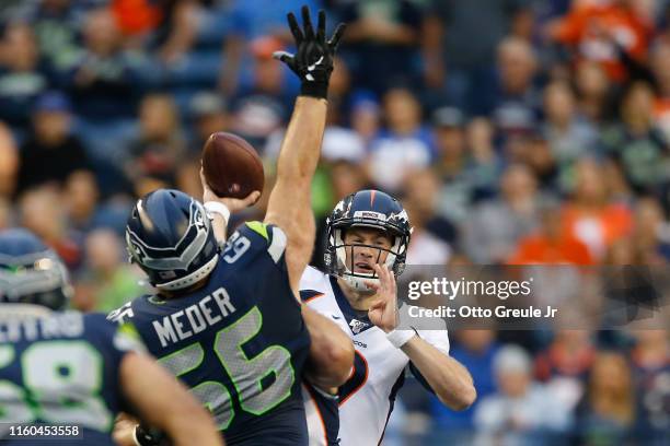 Quarterback Kevin Hogan of the Denver Broncos passes against Jordan Simmons of the Seattle Seahawks at CenturyLink Field on August 8, 2019 in...