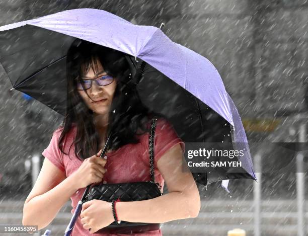 Woman shields herself with an umbrella as she walks in New Taipei City in rain brought by Typhoon Lekima as it passes northeastern Taiwan on August...