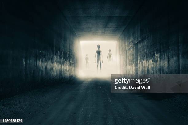 a group of aliens emerging from the light at the end of a dark sinister tunnel. with a high contrast edit. - flying saucer stock pictures, royalty-free photos & images