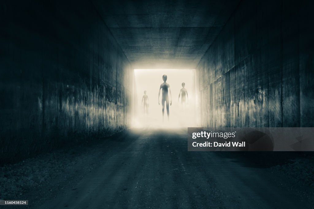 A group of aliens emerging from the light at the end of a dark sinister tunnel. With a high contrast edit.