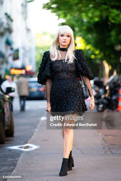 Bonnie Strange wears a black puff sleeves dress with black fabric flowers embroideries, a black Chanel bag, black sock boots, outside the "Scandal A...