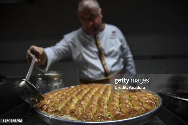 Person pours sharbat on a baklava tray ahead of Eid al-Adha, also called as Feast of the Sacrifice, the second of two religious holidays celebrated...